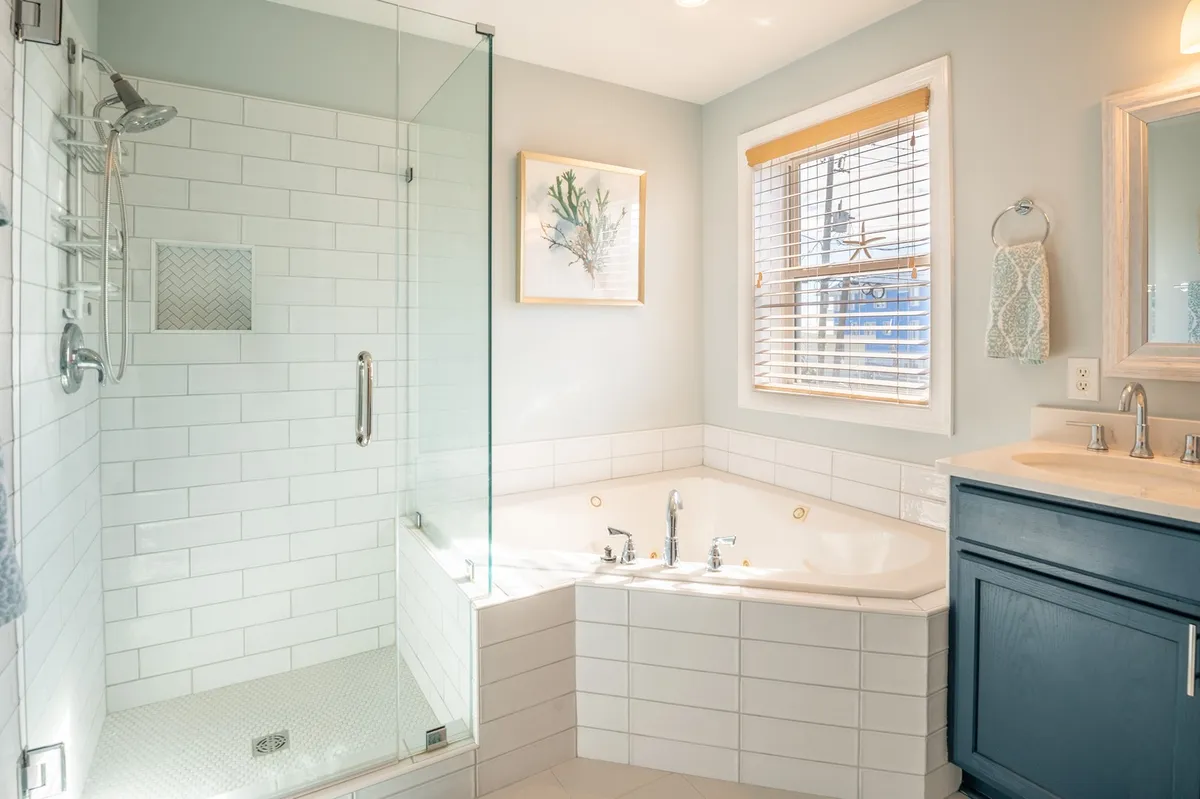 A beautifully designed modern bathroom featuring a freestanding soaking tub, frameless glass shower enclosure, double vanity with mirror, and tasteful decorative artwork. Natural light fills the space, creating a tranquil atmosphere ideal for relaxation and rejuvenation.
