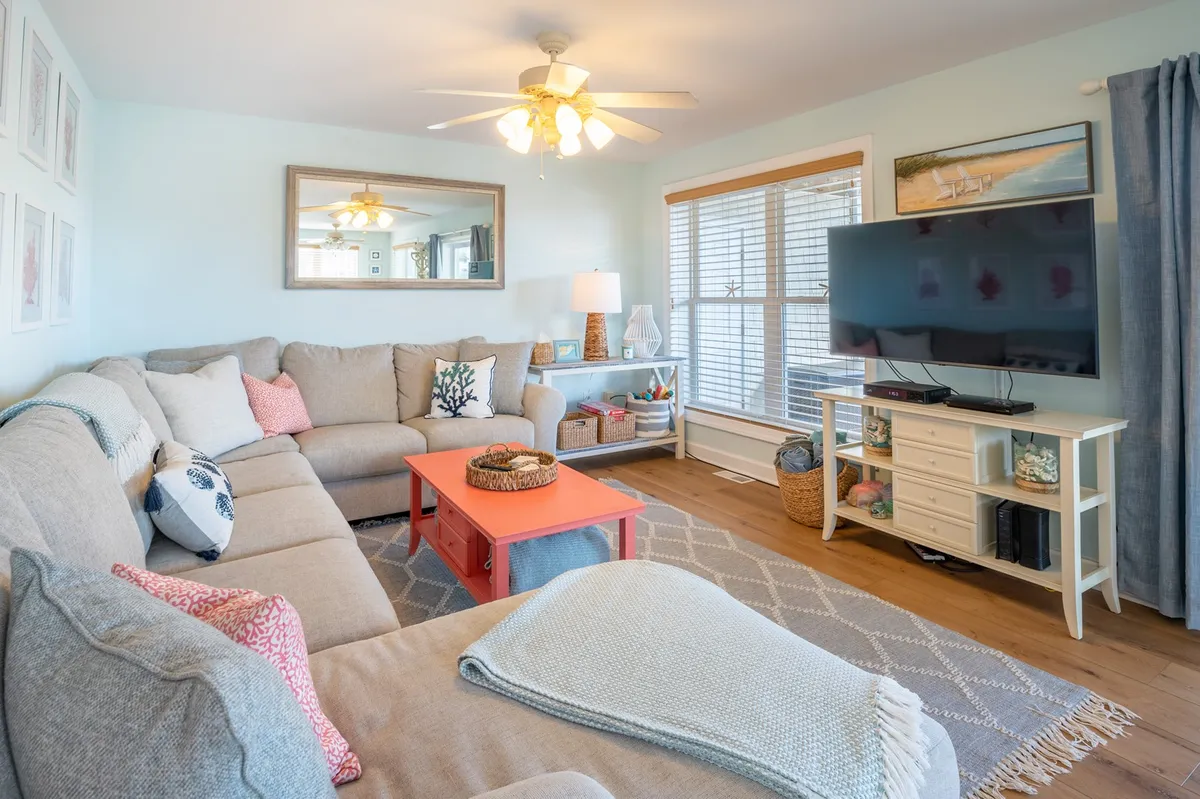 This image presents a comfortable living room scene featuring a sofa, coffee table, television, and a window. The room is designed for relaxation and socializing, with a welcoming and inviting atmosphere that speaks to group gatherings and unwinding after a day of exploration.