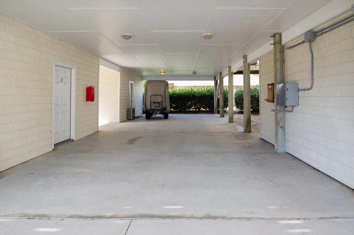 A practical view of the private entryway, showing a covered parking space, a door marked with '2,' and nearby storage utilities. The area is shaded and has a sense of privacy and arrival, hinting at the exclusivity of the porch and entry.