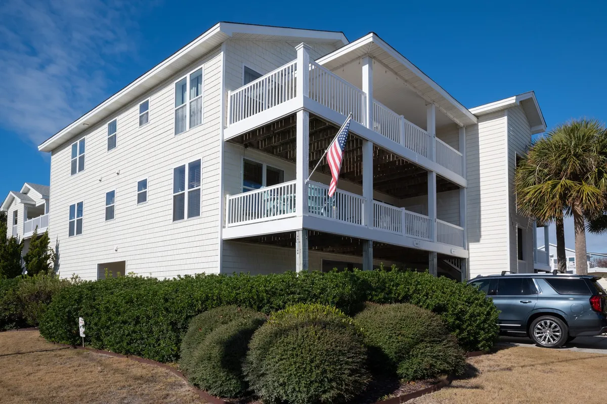 A welcoming exterior shot of the condo building, highlighted by large balconies, manicured landscaping, and an American flag. The setting feels relaxed and inviting, suggesting a comfortable retreat after a day of adventure.